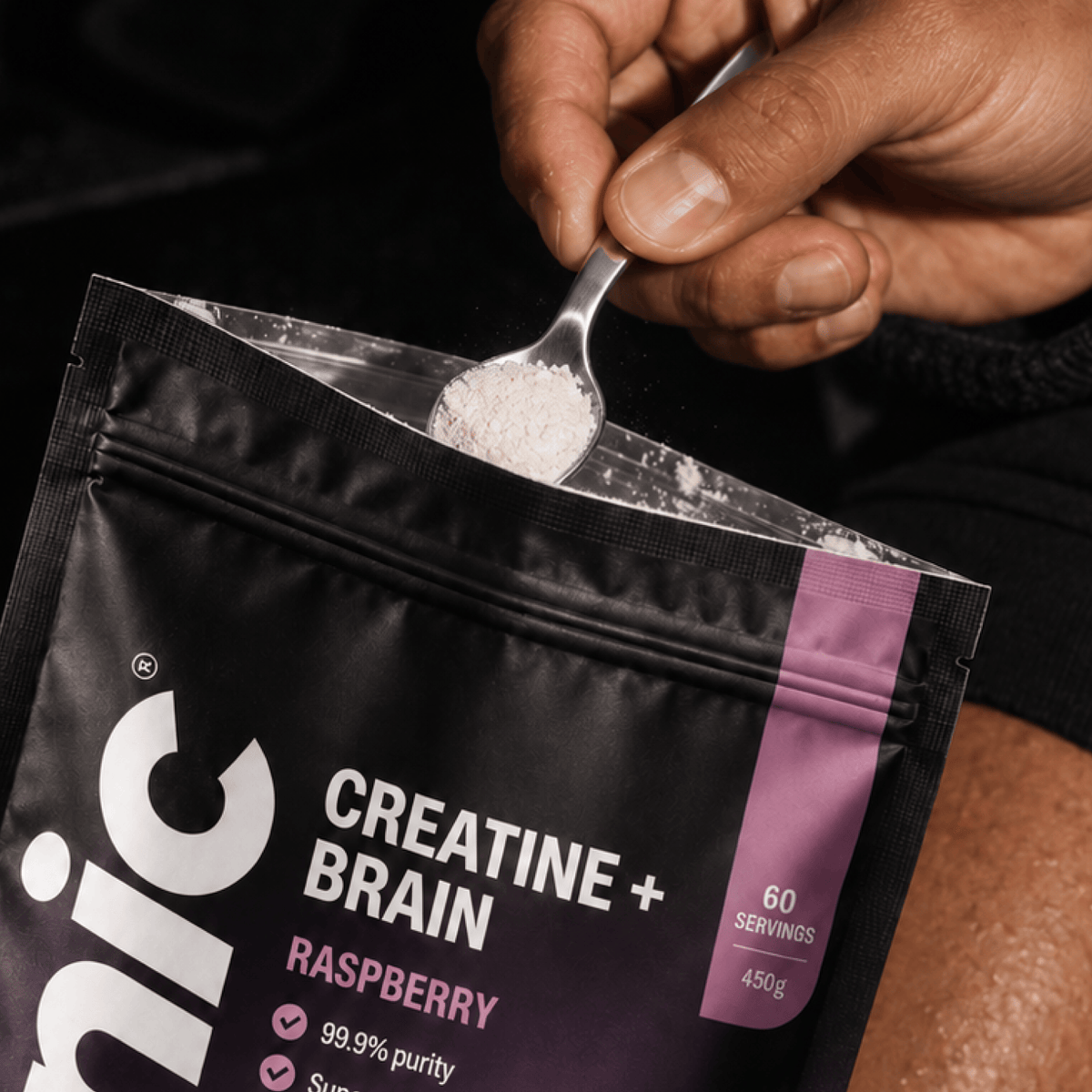 Person uses a teaspoon to scoop the contents of a Tonic Creatine + Brain Pouch