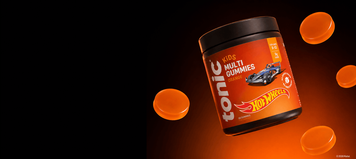 A tub of Tonic KIDS Multi Gummies with a Hot Wheels theme, floating against a black background with orange gummies  around it.