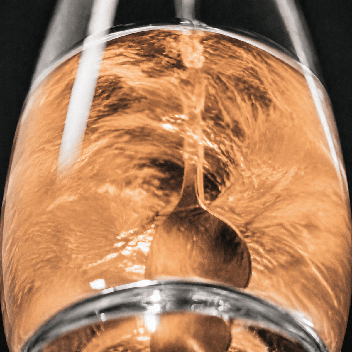 A close-up artistic shot of a clear glass with a spoon inside, filled with Tonic Creatine + Brain, Tropical flavour.