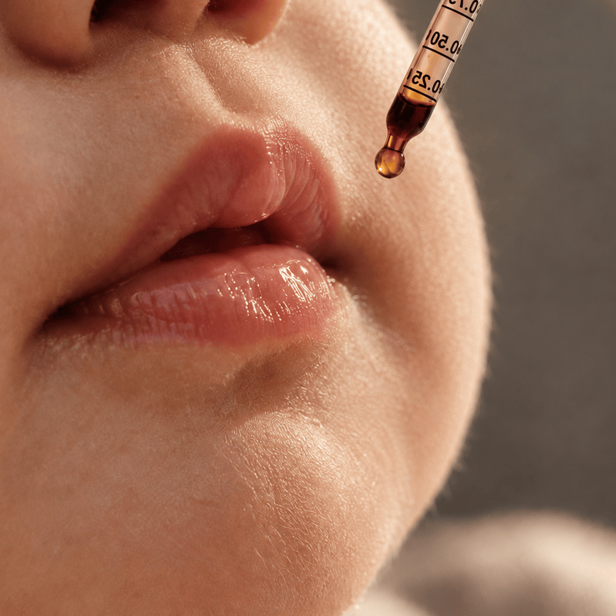 Close-up of a baby's lips and cheek with a glass dropper holding Tonic Baby Vitamin D3 Drops hovering above the skin. 